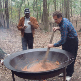 Dave Harwood stirring the chili while Frederick Williams watches.